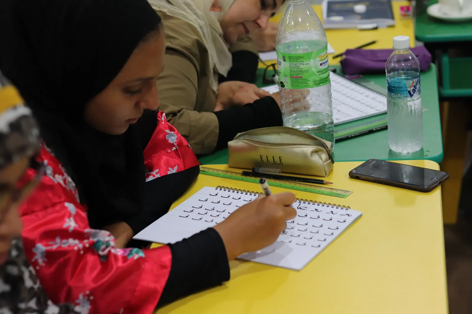 طالبة تتدرب على كتابة الحروف